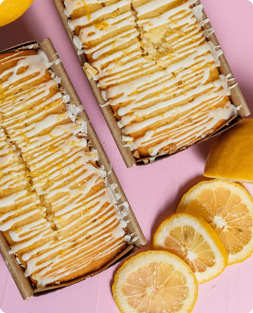 Lemon loaf cakes with white glaze and lemon slices on a pink background