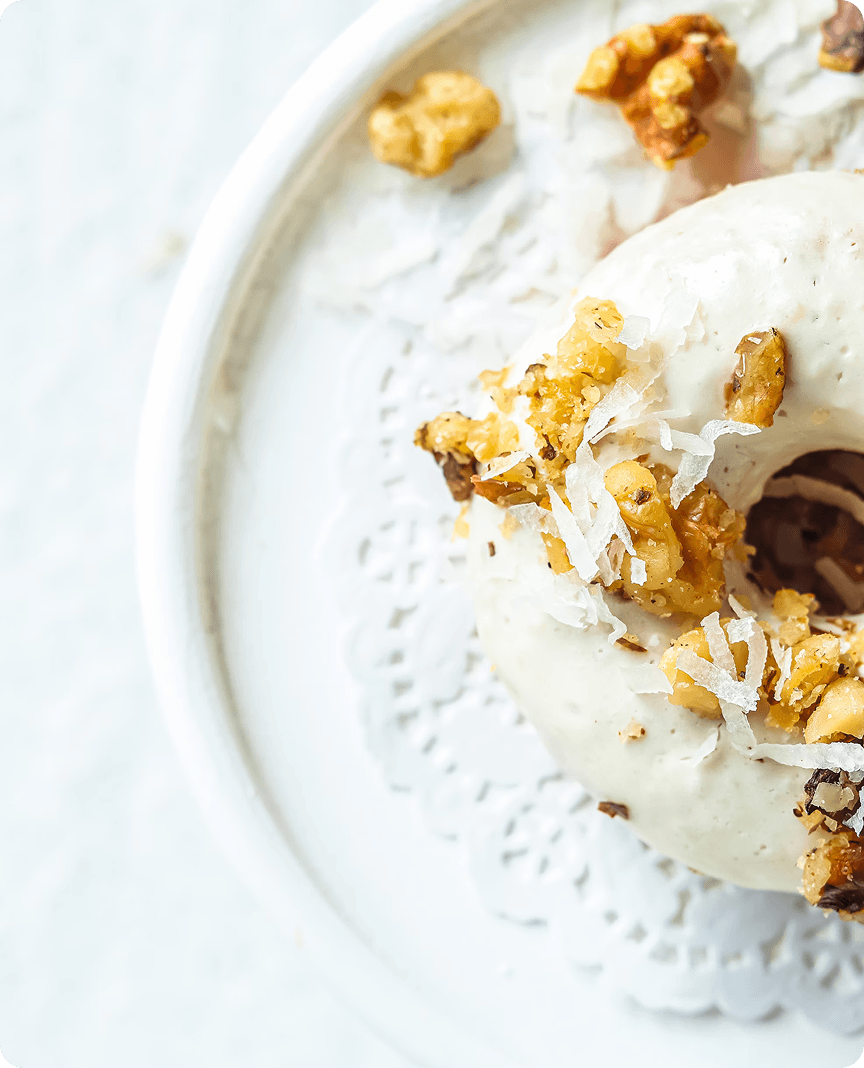 Close-up of a glazed donut topped with coconut flakes and nuts